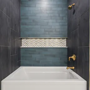 Tub in Second floor bathroom with tile walls and alcove