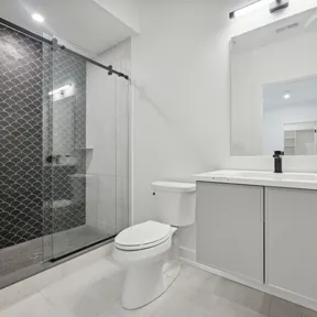 Second floor bathroom with vanity, toilet and shower with glass door and black tiles
