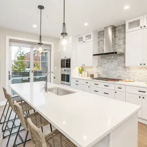 View of the kitchen in The Enclave at Chestnut Hill home featuring white cabinets, high end appliances and large island with sink and seating