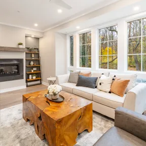 The family room of a home in The Enclave at Chestnut Hill featuring large windows, fireplace, and wide planks of wood flooring