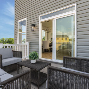 Outside deck with seating area looking through the sliding glass door to the dining room of the Hamilton