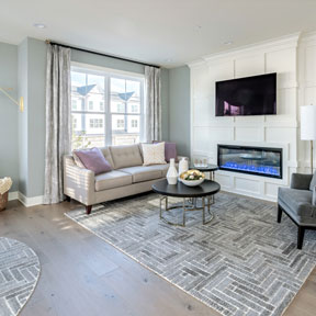 The great room of the model home, Hamilton, featuring large windows, fireplace, and wide planks of wood flooring