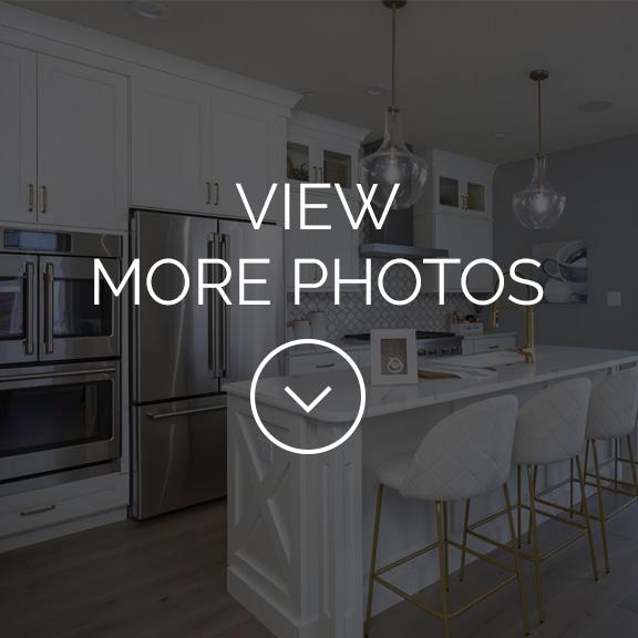 Kitchen of the Hamilton model home with white cabinets, high end appliances and large island with sink and seating