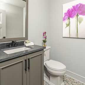 Powder room of the Hamilton model home with toilet and vanity with double door cabinets for storage