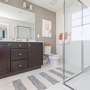 Jordan model owner's bathroom with double vanity, glass shower, window and tile flooring