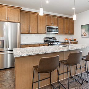 Kitchen of the Jordan model with large island and seating, stainless steel appliances, and hardwood style flooring