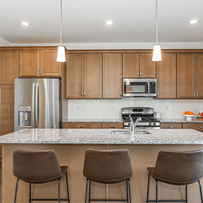 Jordan model kitchen with hardwood style flooring, large island energy efficient appliances, and wood cabinets