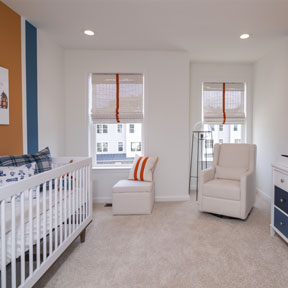 Bedroom at the Jordan model home setup as a nursery with double windows and wall to wall carpeting