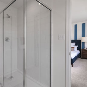 Owner's en suite bathroom with glass stall shower and view of bedroom.
