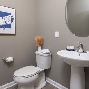 Powder room of the Jordan model with hardwood style flooring, toilet, and pedestal sink