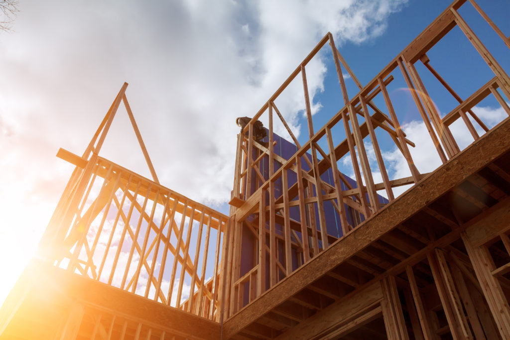 Bight blue, cloudy sky with a frame of a home being built.