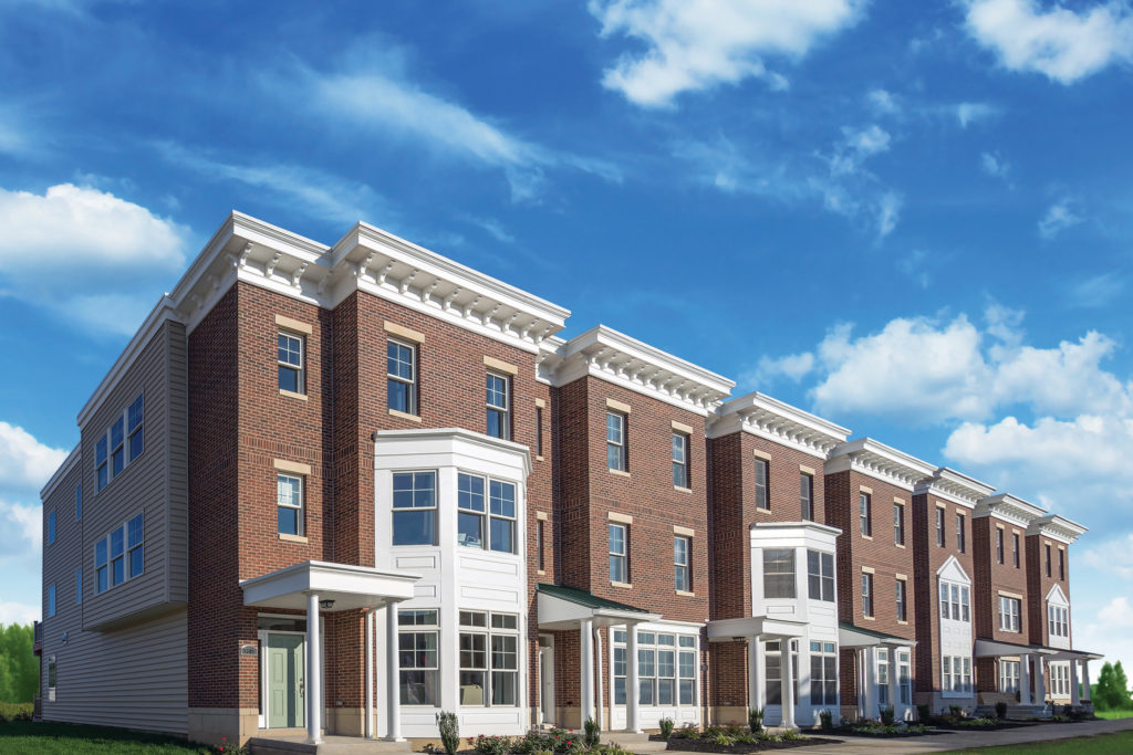 Exterior brick townhomes with bright blue cloudy sky.