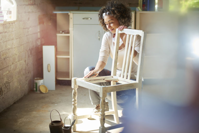 A woman restores and improves an old wooden chair in her workshop