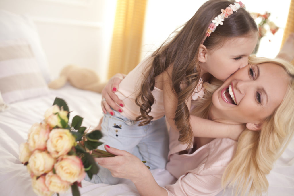 Cute little daughter embracing her mother.