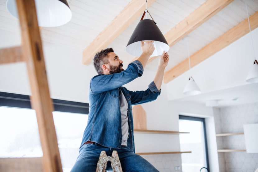 Man installing new lighting fixtures in his new construction home.
