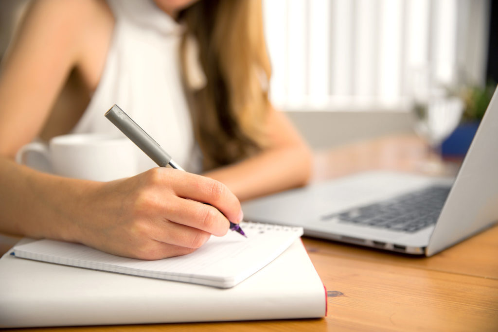 Woman writing new years resolutions on a notepad